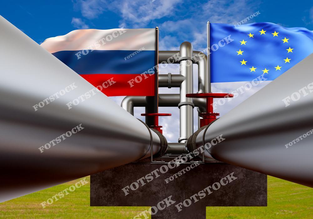 На изображении показан крупный трубопровод с флагами России и Европейского Союза на фоне голубого неба. Красные вентили подчеркивают контроль поставок и технологический аспект инфраструктуры. Фотография иллюстрирует энергетическое сотрудничество и геополитические связи между регионами.
